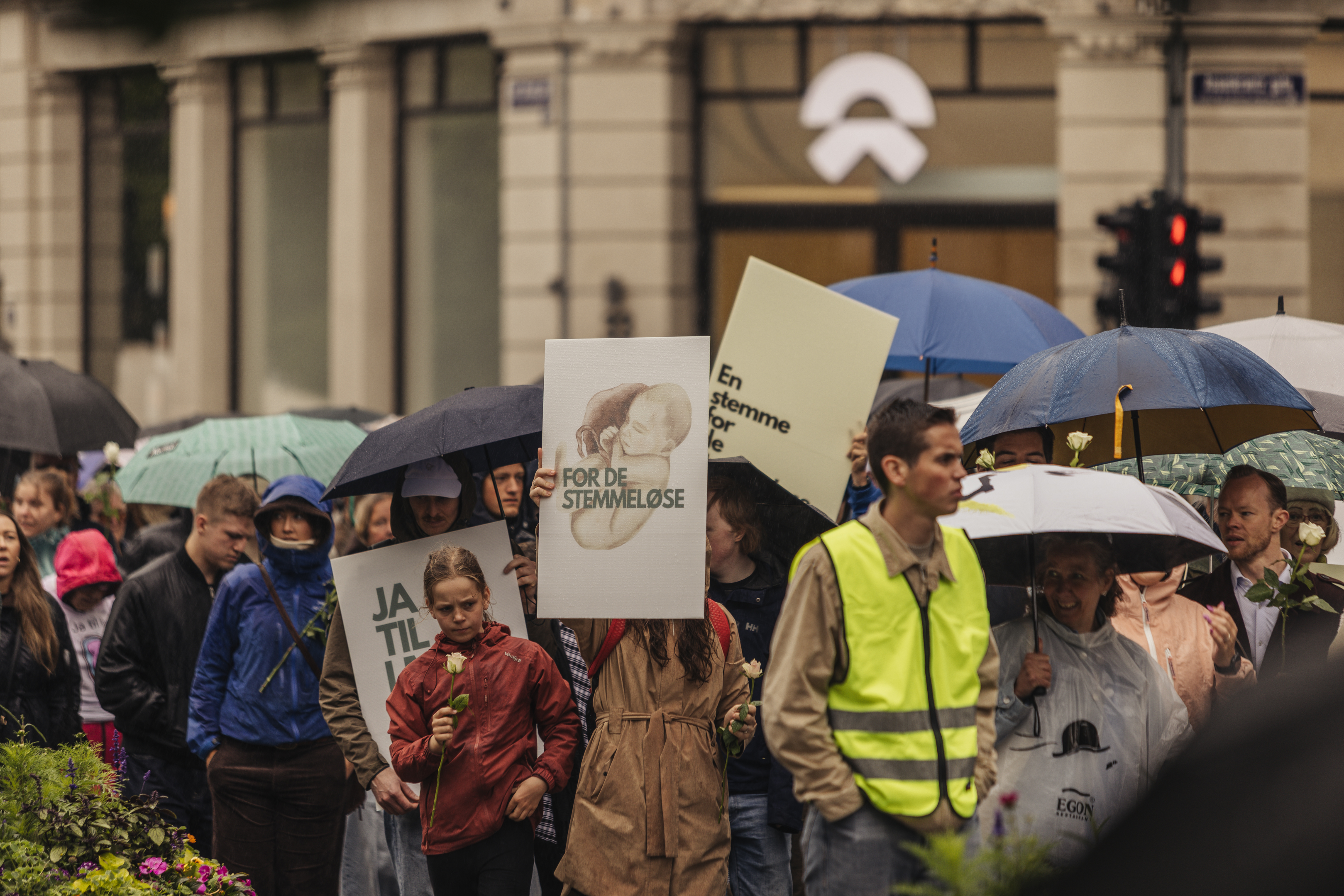 Participants walk under umbrellas in the rain, one holding a sign reading “For de Stemmeløse” (“For the Voiceless”), during the March for Life in Oslo, Norway, on June 13, 2026. | Credit: Bendik Bruun Edvardsen