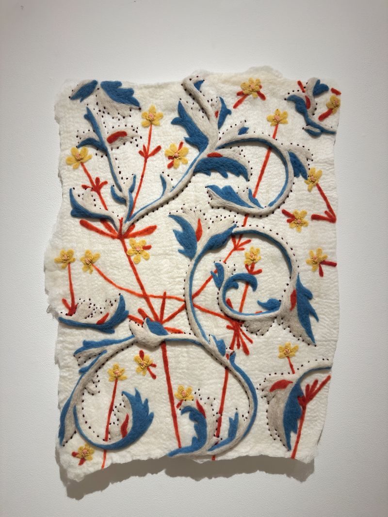 A depiction of buttercups, “Delight” is made with wet and needle felting sheep wool and embroidery with naturally dyed wool yarns and is on display at the “Hand in Hand” art display. | Credit: Holly Guertin