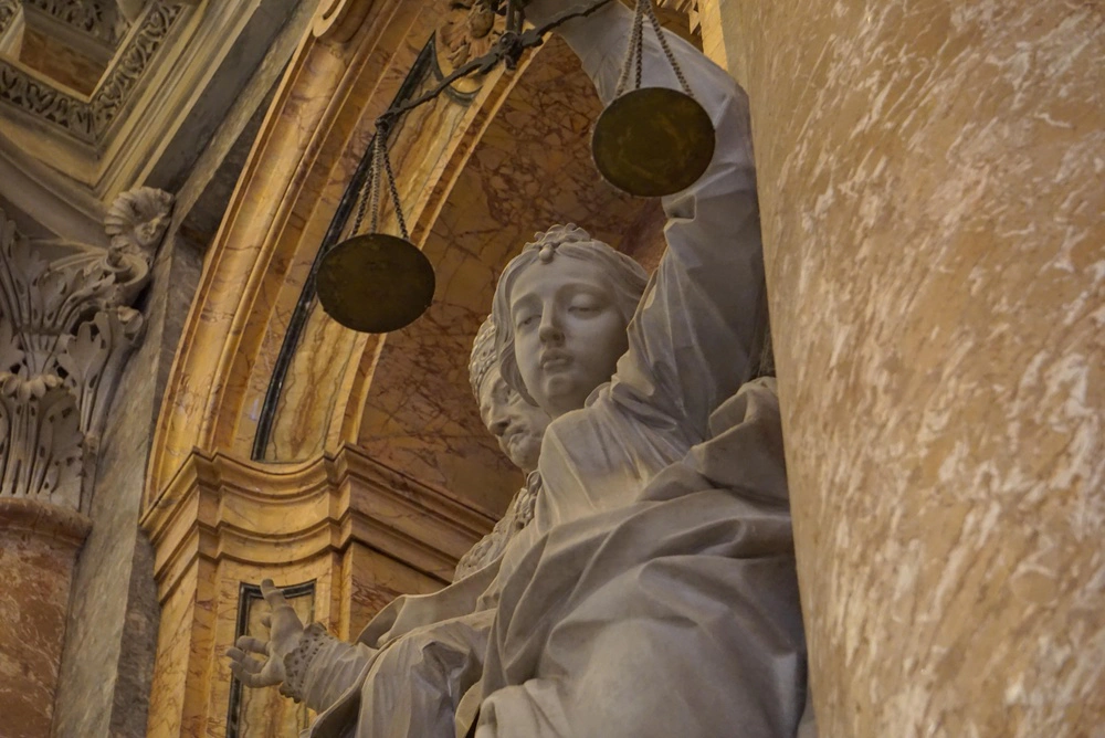 Detailed close-up of a Renaissance marble statue depicting Lady Justice, the ancient Roman goddess Justitia, with scales inside St. Peter’s Basilica at the Vatican. | Credit: Alexander Ruszczynski/Shutterstock